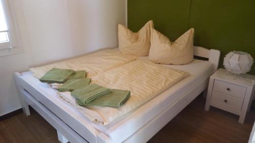 uma cama branca com duas toalhas verdes em Ferienhäuser Stübgen em Burg