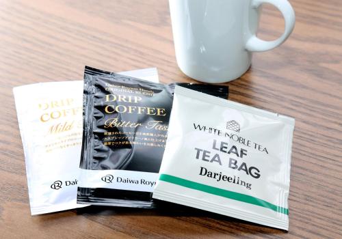 two tea bags sitting next to a cup of coffee at Daiwa Roynet Hotel Sendai Ichibancho PREMIER in Sendai