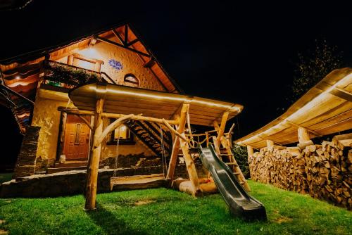 a playground with a slide in front of a house at Bajeczny domek Andrzejówka in Polańczyk