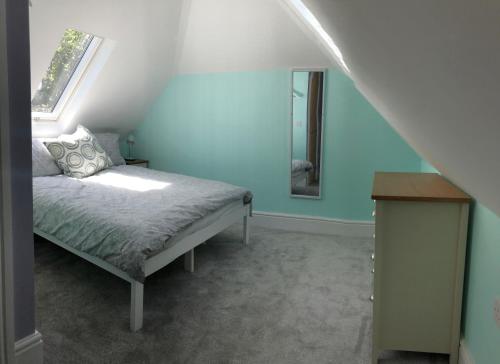 a bedroom with blue walls and a bed with a mirror at The Annex, Manor Road, Didcot in Didcot