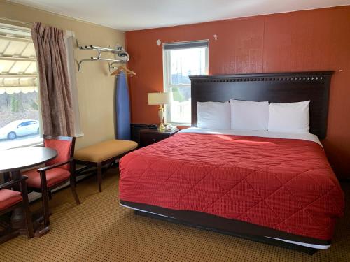 a hotel room with a bed and a table and a window at Budget Inn in Belle Vernon