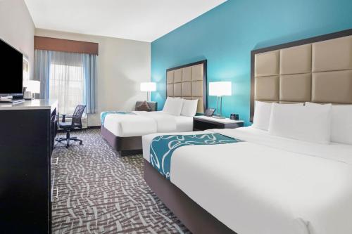 a hotel room with two beds and a desk at La Quinta Inn and Suites by Wyndham Paris in Paris