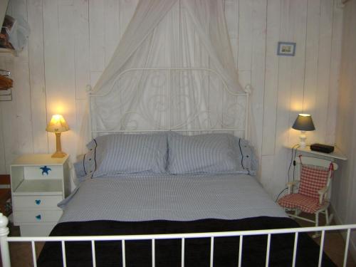 a bed with a white headboard in a bedroom at La Petite Maison sur l'Ile de Ré in La Flotte