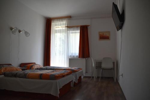 a bedroom with two beds and a television in it at Tihany Község Önkormányzat - Ifjúsági Szállás in Tihany
