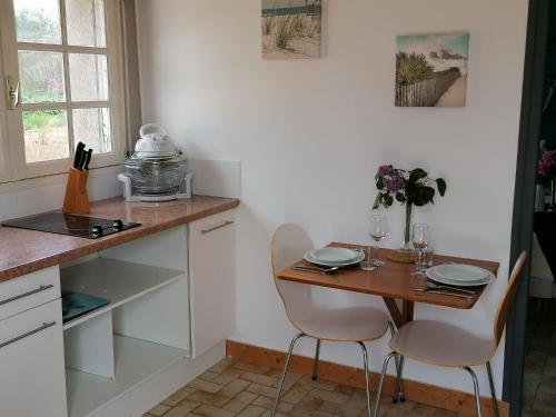 une petite cuisine avec une table et des chaises en bois dans l'établissement Proche Le Pouldu, cadre verdoyant avec parking, à Clohars-Carnoët