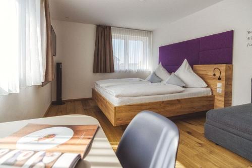 a hotel room with a bed and a chair at Hotel Restaurant Kochschule Rössle in Elzach