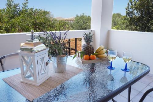 a glass table with fruit and wine glasses on a balcony at Olive House in Malia