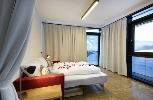 ein Schlafzimmer mit einem weißen Bett und einem großen Fenster in der Unterkunft Thurnbach - Top Level Apartments in Aschau