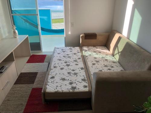 a couch in a living room next to a window at Apt de frente e com vista Lagoa in Arraial do Cabo