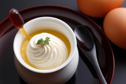 a bowl of soup with whipped cream and a spoon at The Shiroyama Terrace Tsuyama Villa in Tuyama