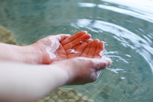 a person holding their hands in the water at The Shiroyama Terrace Tsuyama Villa in Tuyama
