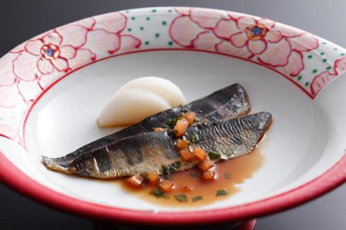 a plate of food with fish in a sauce at The Shiroyama Terrace Tsuyama Villa in Tuyama