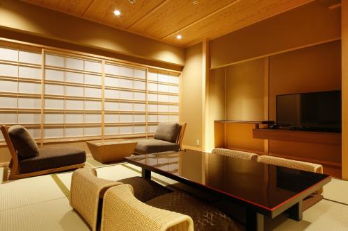 a living room with a table and chairs and a tv at The Shiroyama Terrace Tsuyama Villa in Tuyama