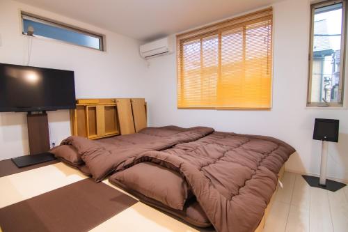 een slaapkamer met een groot bed en een flatscreen-tv bij Convertel Honhaneda in Tokyo
