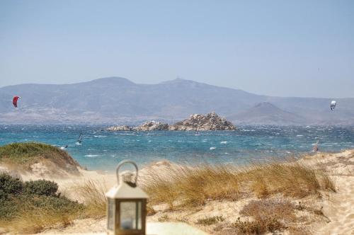a light on a beach with people flying kites in the water at Studios Kontos in Mikri Vigla
