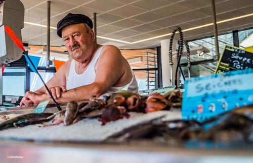 un homme se tenant derrière un comptoir sur un marché de poissons dans l'établissement Villa le Hameau - Cap Esterel (Agay), à Saint-Raphaël