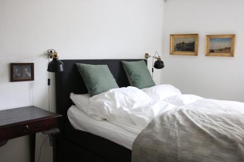 a bed with white sheets and green pillows at Tøndegården 3 rooms apartment in Odense
