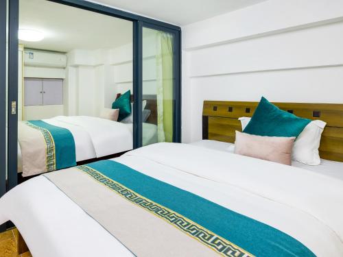 a bedroom with two beds and a mirror at April Fair Duplex Apartment Guangzhou South Railway Station Ao Yuan Yue Shi Dai Branch in Guangzhou
