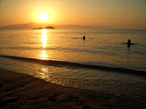 two people in the water at the beach at sunset at Studios Kontos in Mikri Vigla