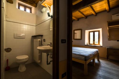 a bathroom with a toilet and a sink and a bed at Ostello Podesteria di Gombola - arte e territorio in Polinago
