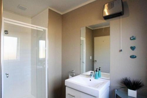 Un baño con lavabo blanco y ducha. en Harakeke House Downstairs - Ohakune Unit, en Ohakune