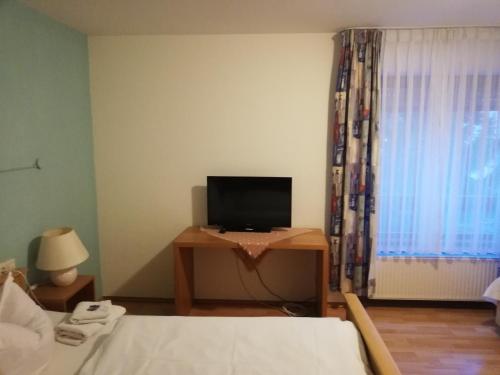 a bedroom with a bed and a desk with a television at Hotel Linde in Biberach-Ummendorf