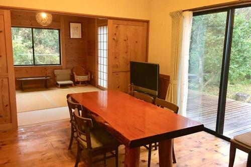 a dining room with a wooden table and a television at 屋久島シエスタYakushima Entire house with a wonderful view in Yakushima