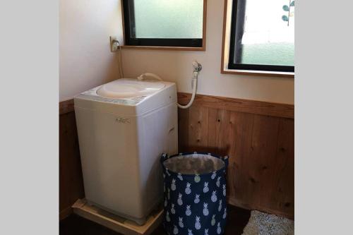 a small bathroom with a washing machine and a trash can at 屋久島シエスタYakushima Entire house with a wonderful view in Yakushima