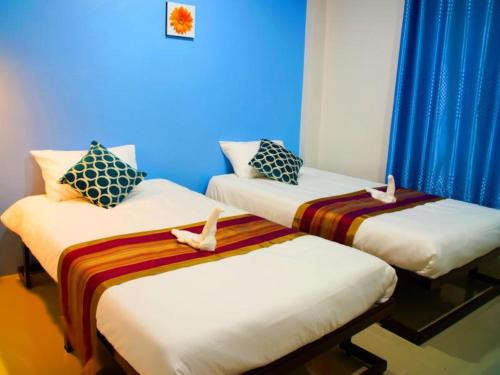 two beds in a room with blue walls and blue curtains at Na Dream Place in Suratthani