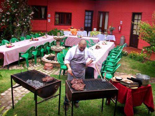 a man is cooking meat on a grill at Posada del Parque in Concón