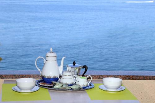 a tray with tea pots and cups on a table near the water at La Petronilla in Castelsardo