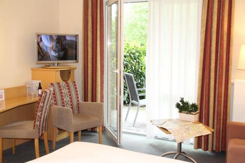 a hotel room with a table and chairs and a television at Landhotel Hermannshöhe in Legden