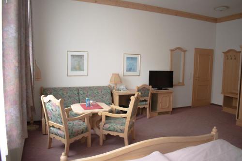 a living room with a couch and a table and a television at Pension Haus Marga in Wernigerode