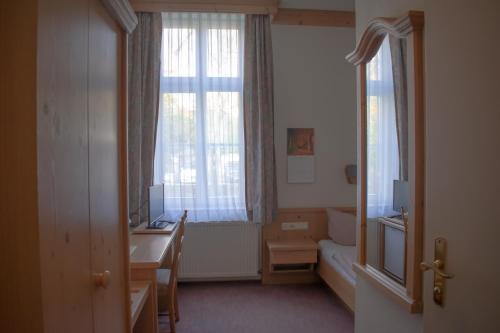 a small room with a desk and a window at Pension Haus Marga in Wernigerode
