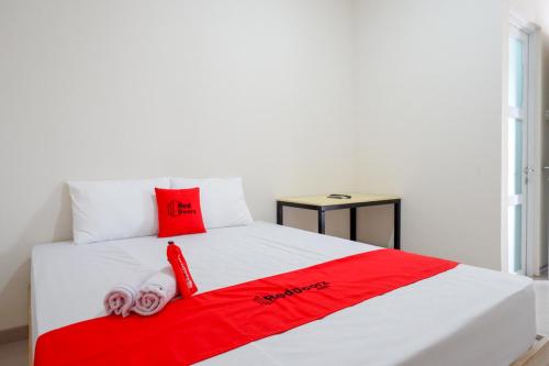 Cama blanca con almohadas rojas y manta roja en RedDoorz near Lippo Plaza Buton en Baubau