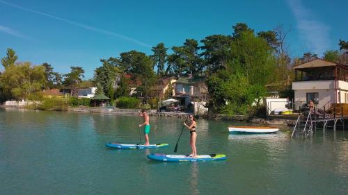 two women are standing on paddle boards in the water at Royal Mediterran in Siófok