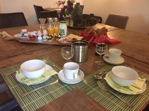 a wooden table with plates and bowls and glasses on it at B&B De Willemshoeve in Wageningen