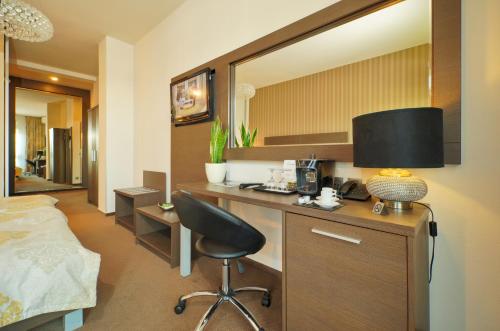 Hotel Centrum في نيترا: غرفة نوم مع مكتب مع كرسي وسرير