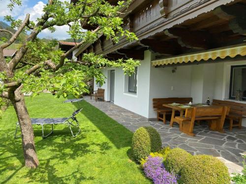 a patio with a table and a bench in a yard at Ferienwohnung Apartment Haus Ager in Thiersee