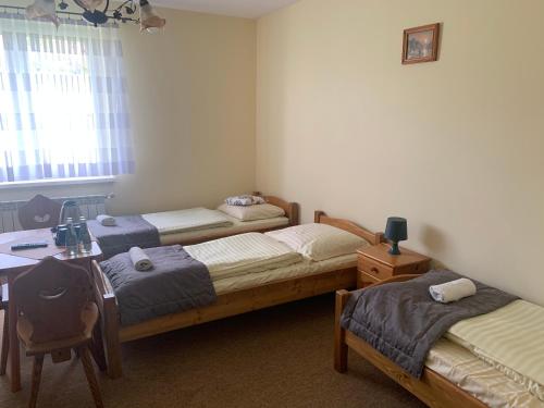a bedroom with three beds and a desk and a table at Willa Karolina in Czorsztyn