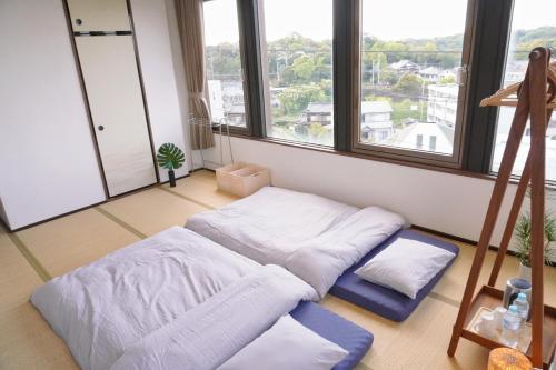 a room with two beds and two large windows at Japanese House Osaka Sennan Hotel（大阪泉南酒店和築） in Tannowa