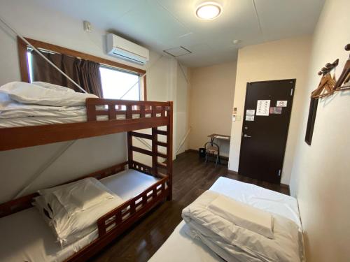 2 łóżka piętrowe w pokoju z oknem w obiekcie Nomad Hostel East w Tokio