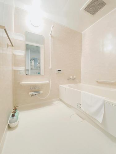 a white bathroom with a tub and a sink at OUCHI HOTEL Otemachi in Hiroshima