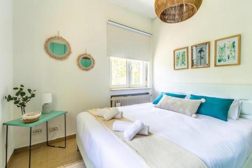 een slaapkamer met een groot wit bed en een tafel bij Molho 2BR for 6 guests in Jeruzalem