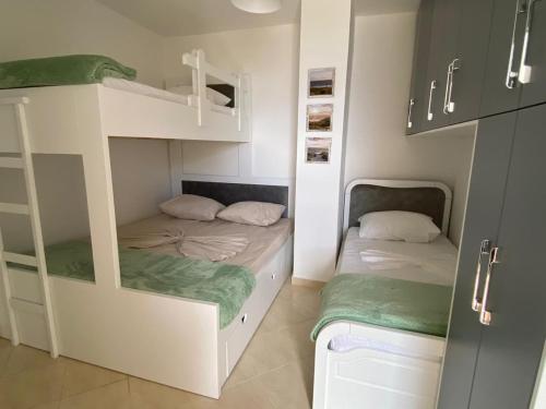 2 łóżka piętrowe w małym pokoju z zielonymi ręcznikami w obiekcie Sun & Sea Apartment Saranda w Sarandzie