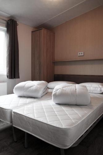 a bedroom with two beds with white pillows on them at Beach Chalet Tranquilo in Petten