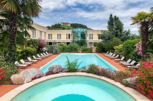 a swimming pool with chairs and a building at Hotel Touring in Coccaglio