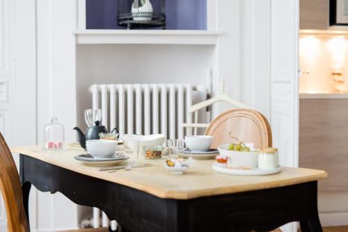 - une table en bois avec des tasses et de la vaisselle dans l'établissement Maison Ailleurs, à Chartres