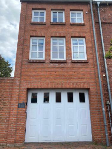 un bâtiment en briques avec deux portes de garage blanches dans l'établissement Ferienwohnung Altstadt Perle_ 15164, à Leer