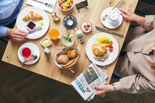 people sitting at a table with breakfast food and a newspaper at BUITERLING Hotel in Brilon